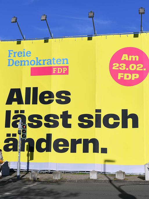 An einer Straße in Düsseldorf steht ein großes Wahlplakat der FDP zur Bundestagswahl 2025, auf dem in großen Buchstaben "Alles lässt sich ändern" steht.