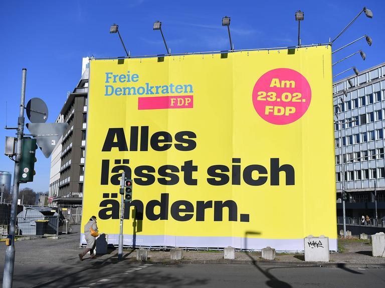 An einer Straße in Düsseldorf steht ein großes Wahlplakat der FDP zur Bundestagswahl 2025, auf dem in großen Buchstaben "Alles lässt sich ändern" steht.