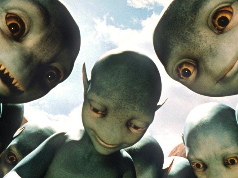 Feindlich gesinnte Aliens beäugen im Kinofilm "Galaxy Quest - Planlos durchs Weltall" (Szenenfoto) auf einem real existierenden fernen Planeten menschliche Besucher.