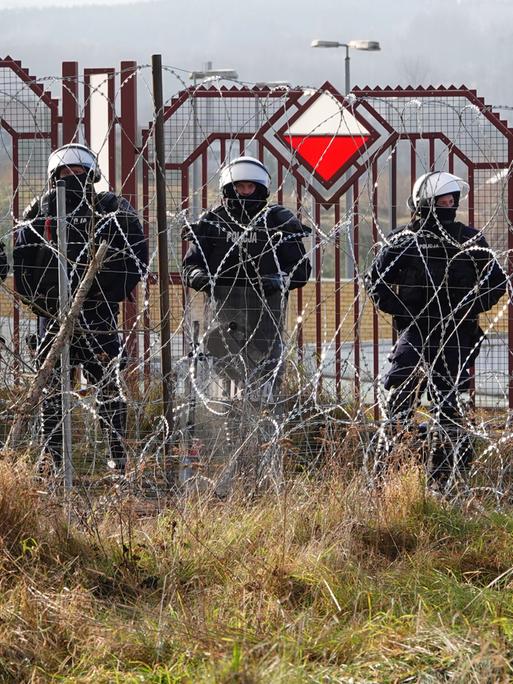 Polnische Sicherheitskräfte stehen an der Grenze hinter Stacheldraht.