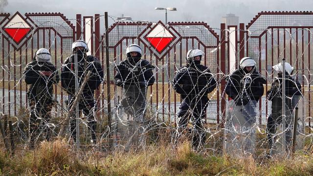 Polnische Sicherheitskräfte stehen an der Grenze hinter Stacheldraht.