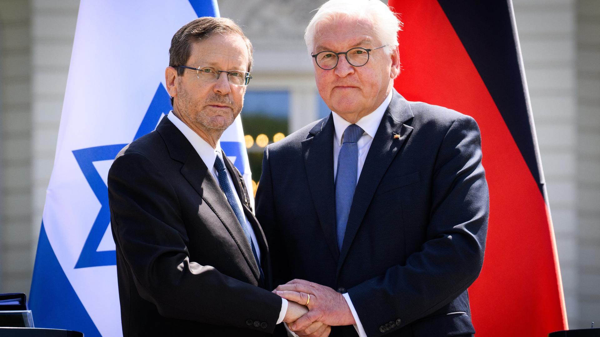 Israels Staatspräsident Herzog und Bundespräsident Steinmeier geben sich die Hand. Im Hintergrund die isrsaelische und die deutsche Flagge. Israels Staatspräsident Herzog und Bundespräsident Steinmeier geben sich die Hand. Im Hintergrund die isrsaelische und die deutsche Flagge.