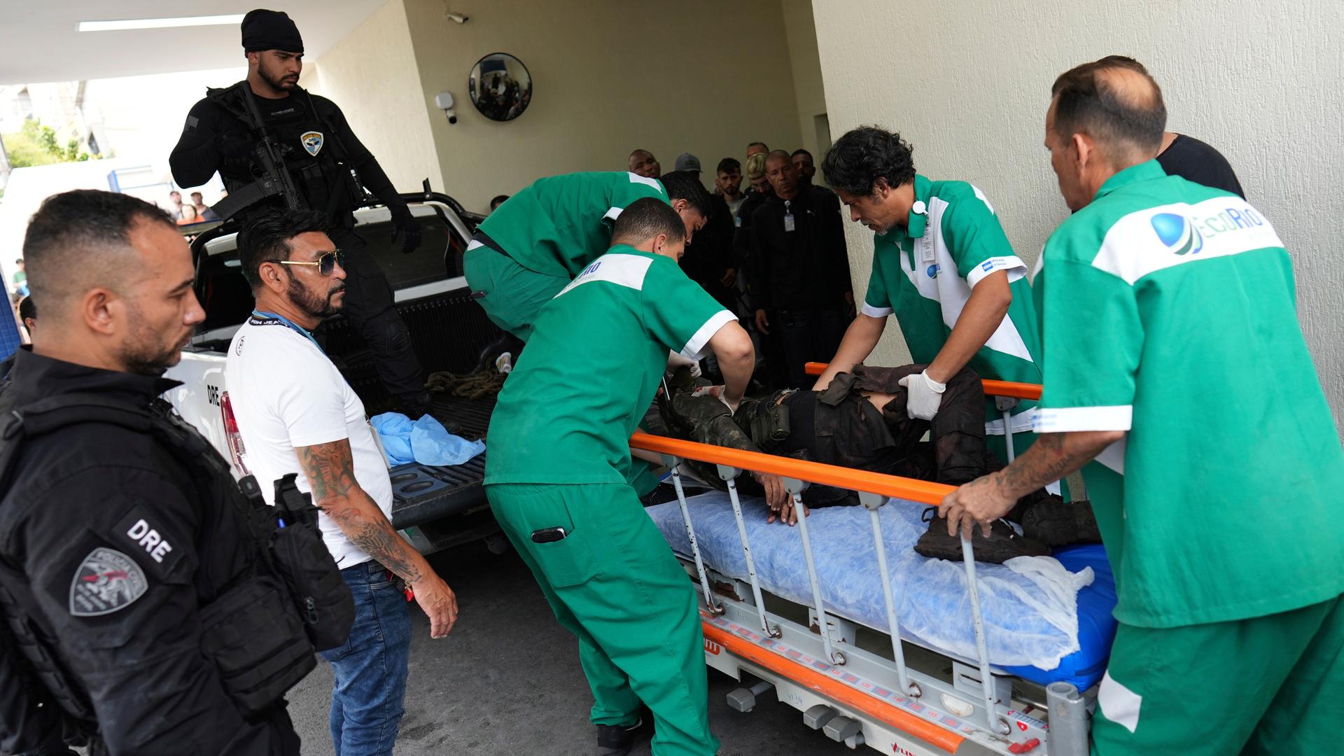 Mitarbeiter eines Krankenhauses bringen einen Verletzten auf eine Trage. An der Seite stehen Polizisten.