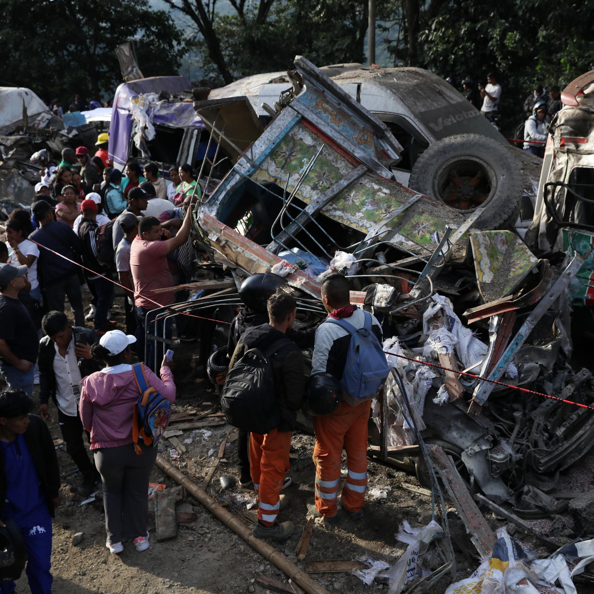 Menschen stehen zwischen zerbeulten und ausgebrannten Autos. 