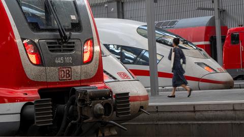 Zugreisende gehen an Zügen der Deutschen Bahn im Münchner Hauptbahnhof vorbei.