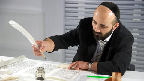 Der Rabbiner Reuven Yaacobov schreibt mit Feder und Tinte im Jüdischen Museum Berlin eine Torarolle.