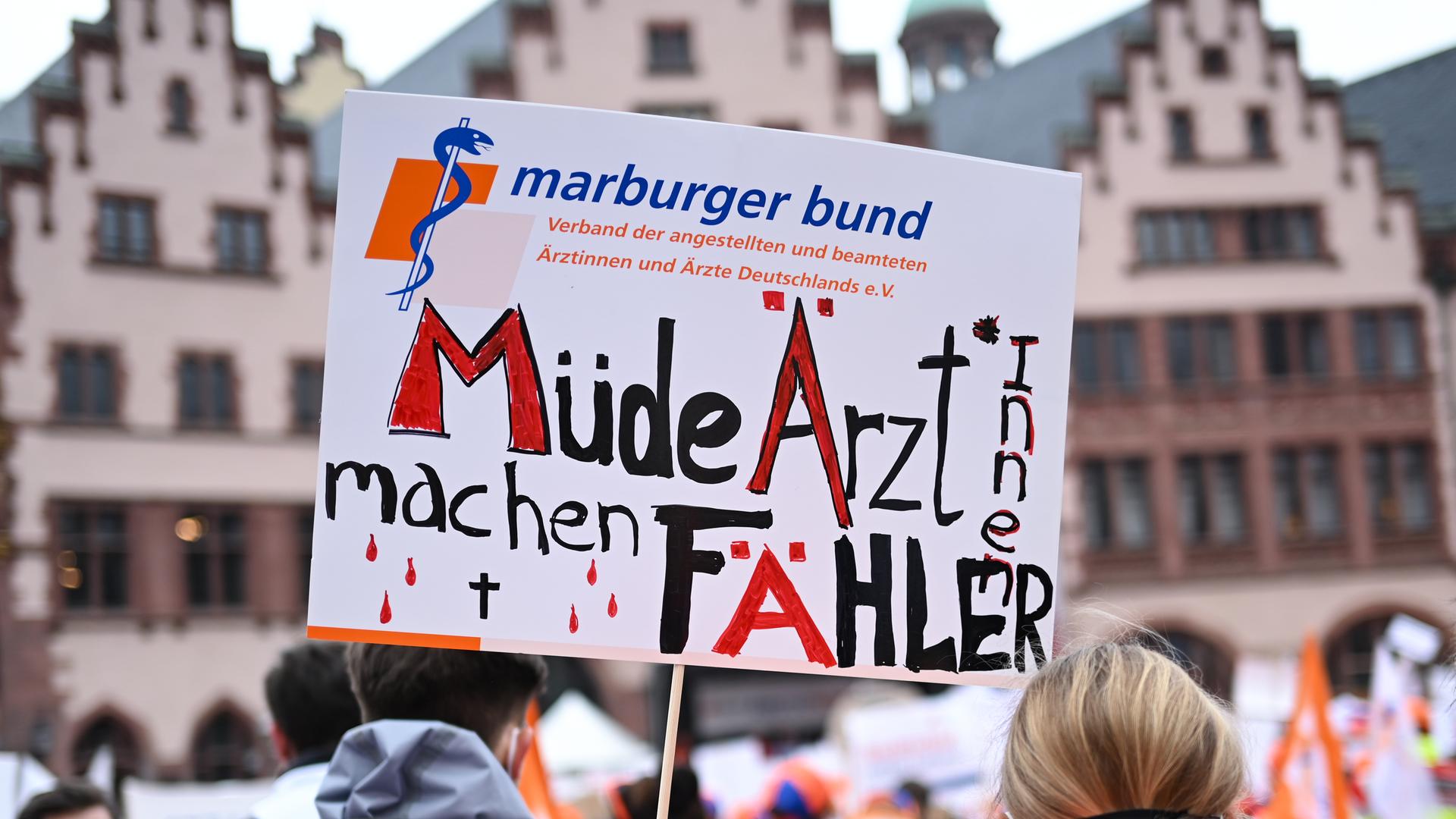 Eine Frau hält bei einer Kundgebung des Marburger Bund auf dem Römerberg ein Plakat mit der Aufschrift "Müde Ärzt*innen machen Fähler". Das Wort Fehler ist absichtlich falsch mit "ä" geschrieben.