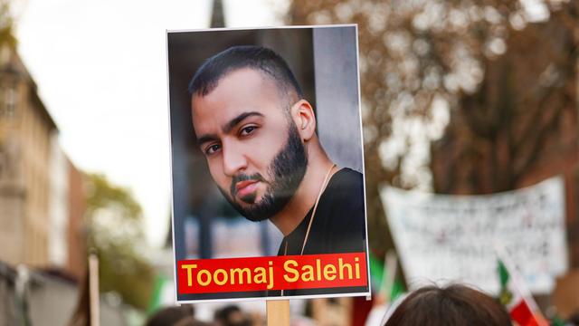 Zu sehen ist ein Bild des Rappers Toomaj Salehi, das auf einer Kundgebung in Köln gezeigt wird.