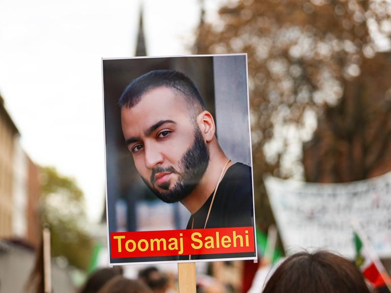 Das Foto zeigt ein Bild des iranischen Rappers Toomaj Salehi auf einer Kundgebung in Köln im November 2022.