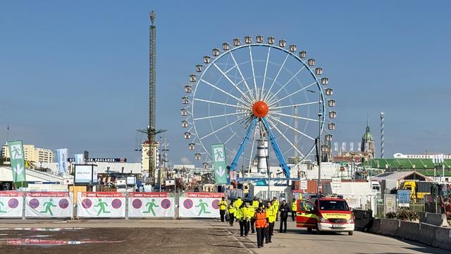 Sicherheits-Kräte stehen vor dem Gelände von dem Oktoberfest. Im Hintergrund ist das Riesen-Rad zu sehen.