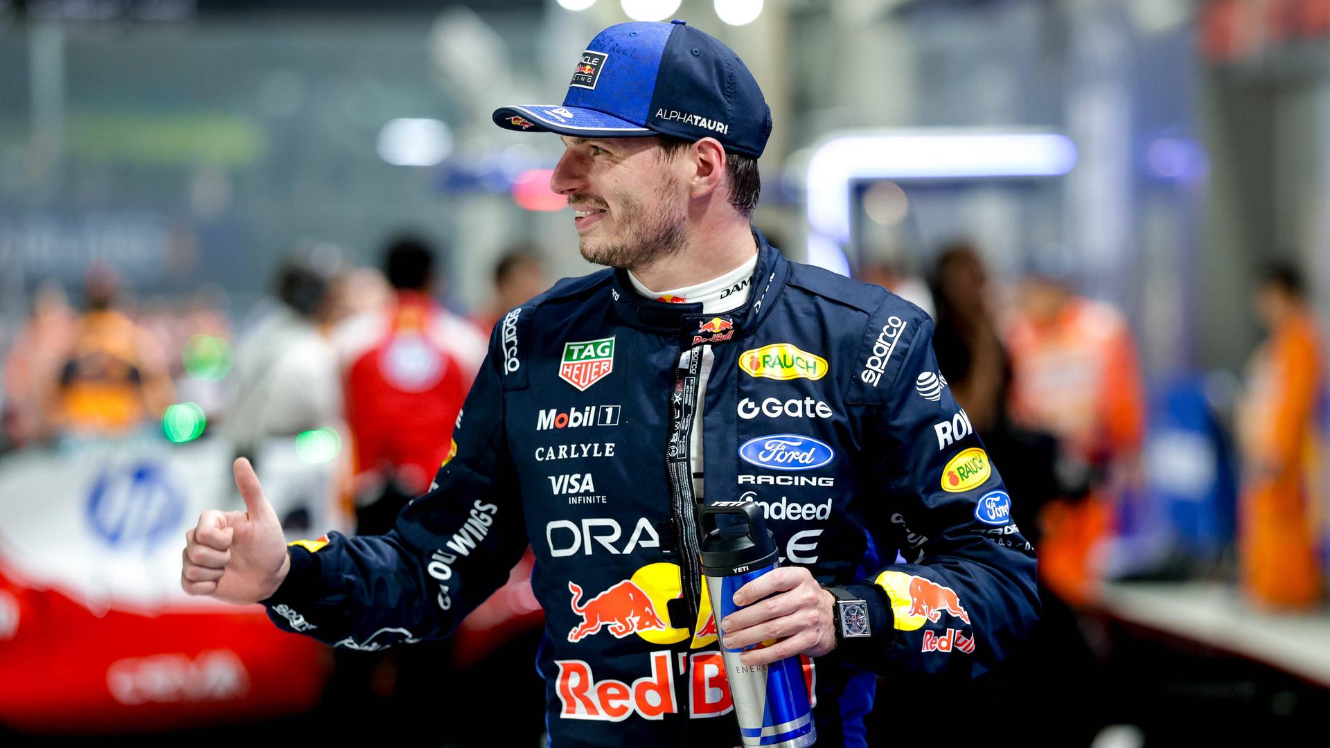 Max Verstappen gewinnt den Großen Preis von Singapur. Er steht an der Rennstrecke, lächelt und hält die rechte Hand mit dem Daumen nach oben.
      