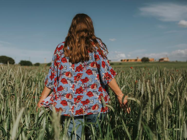 Eine Frau in Rückansicht läuft durch ein Feld