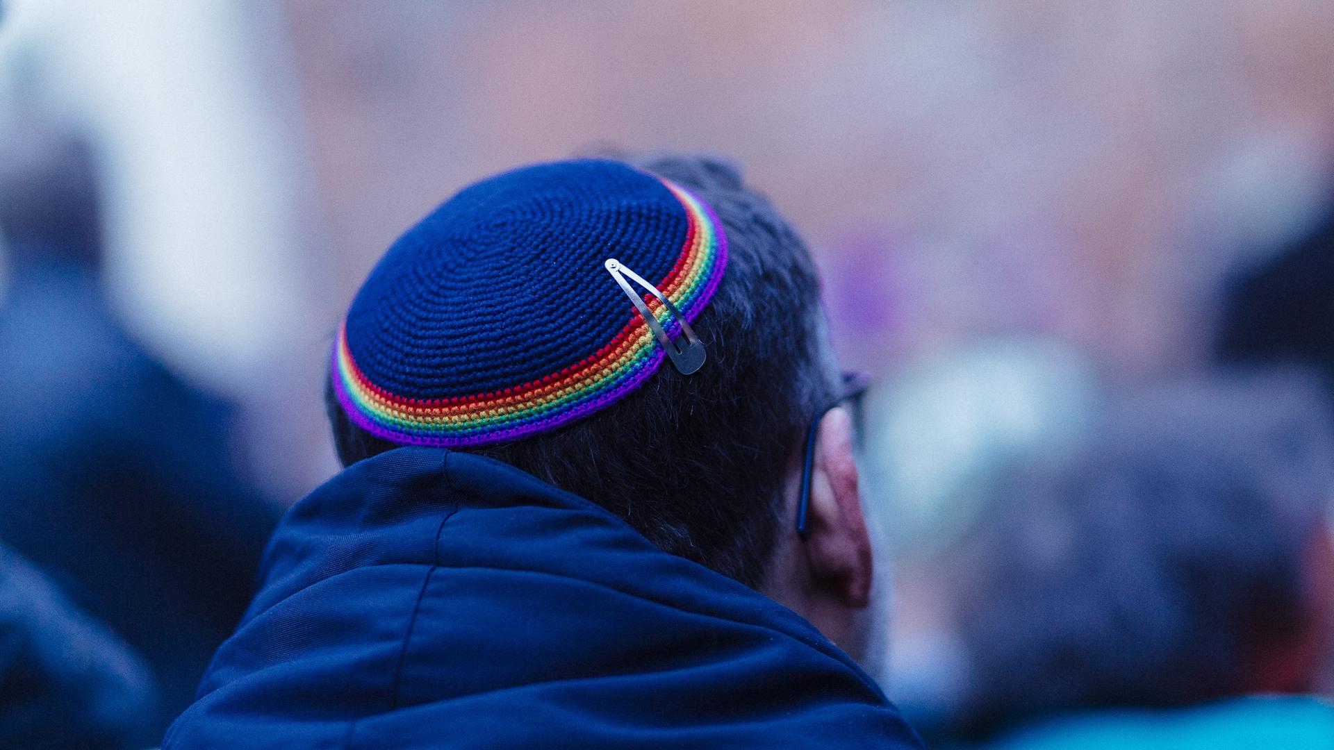 Ein Mann trägt eine Kippa mit einem Saum in Regenbogenfarben.