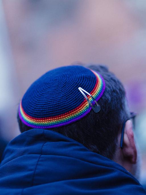 Ein Mann trägt eine Kippa mit einem Saum in Regenbogenfarben.