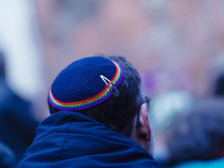 Ein Mann trägt eine Kippa mit einem Saum in Regenbogenfarben.