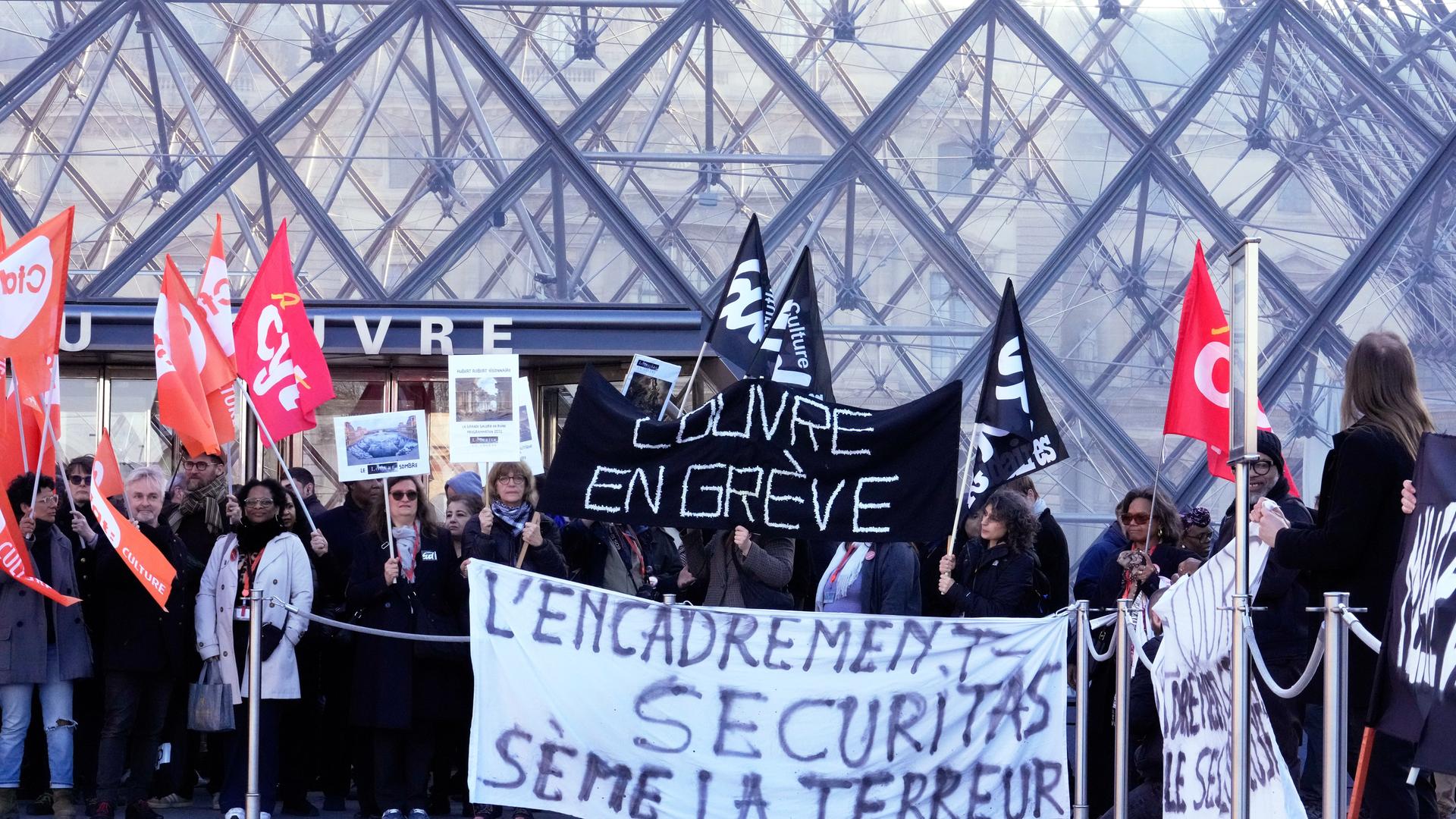 Workers display banners outside the Louvre museum after they voted to strike for the day over working conditions and other complaints, Monday, Dec. 15, 2025 in Paris. (AP Photo/Michel Euler)