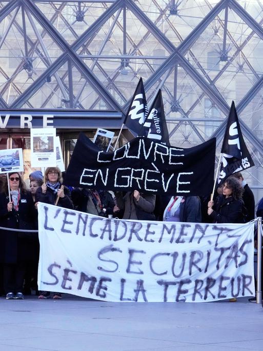 Workers display banners outside the Louvre museum after they voted to strike for the day over working conditions and other complaints, Monday, Dec. 15, 2025 in Paris. (AP Photo/Michel Euler)