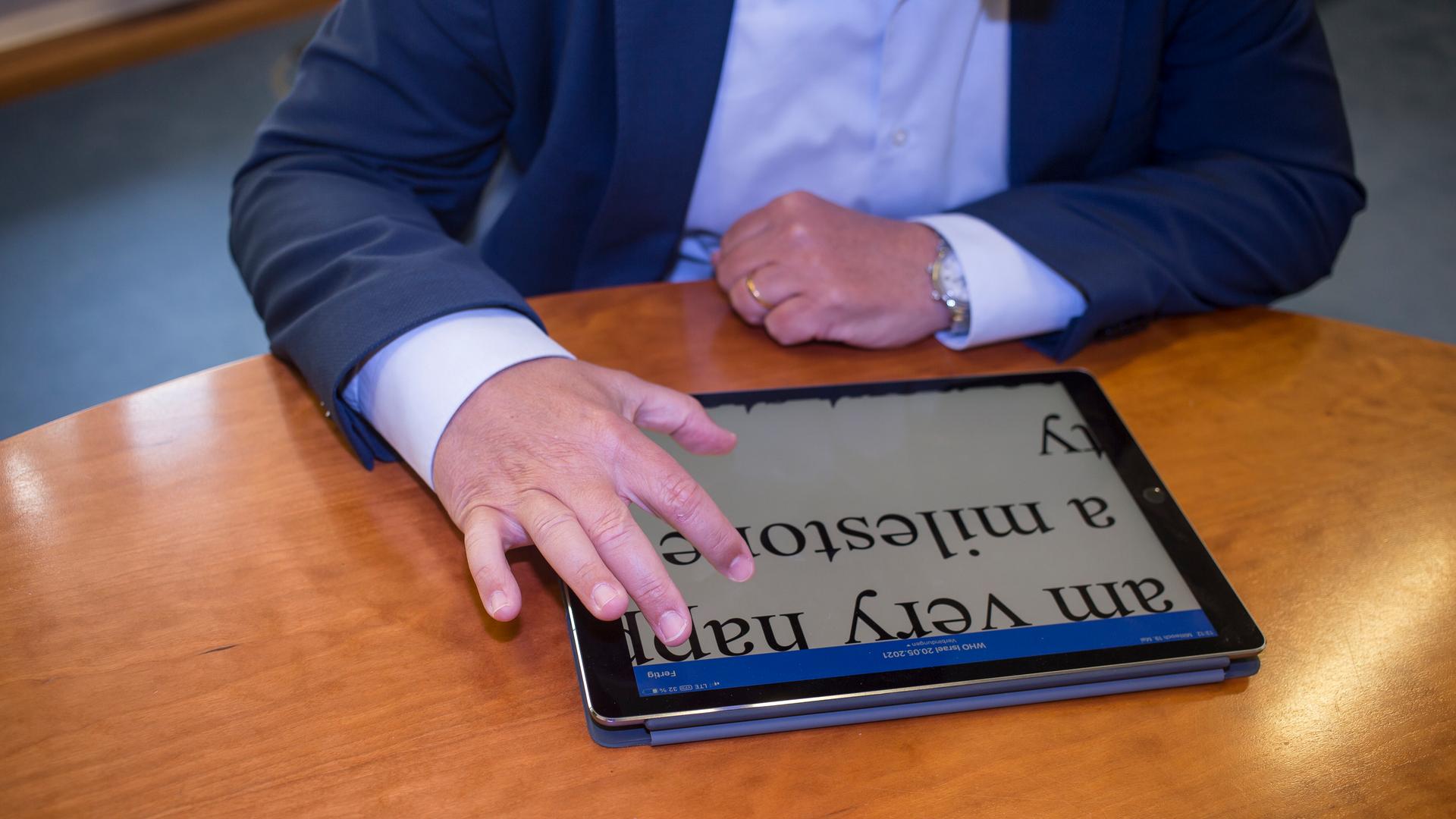 Auf einem Tisch liegt ein Tablet. Die Schrift darauf ist stark vergrößert. Zwei Hände streichen über den Bildschirm. Auf einem Tisch liegt ein Tablet. Die Schrift darauf ist stark vergrößert. Zwei Hände streichen über den Bildschirm.