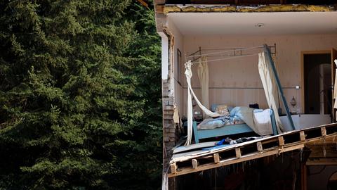 Ein zerstörtes Haus in der Eifel nach der Flutkatastrophe 2021, das Haus zeigt durchgeschnitten ein Schlafzimmer mit Bett, im Hintergrund ein Wald.