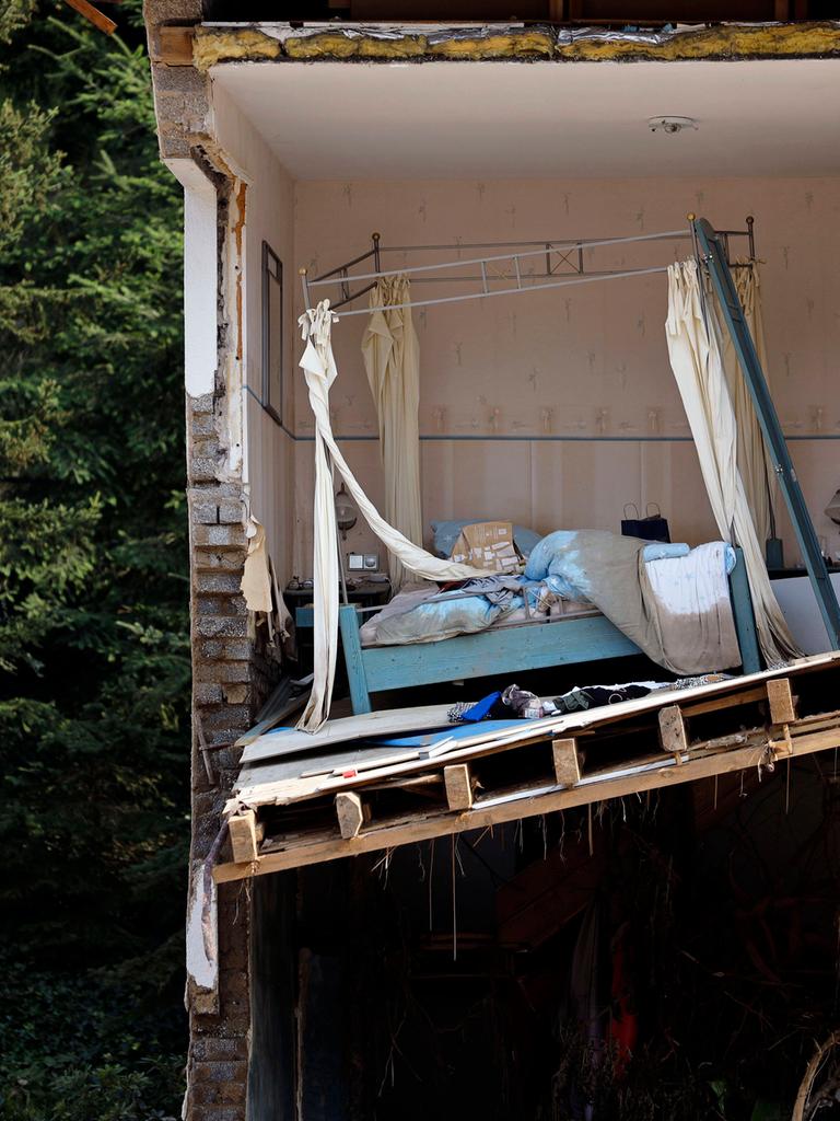 Ein zerstörtes Haus in der Eifel nach der Flutkatastrophe 2021, das Haus zeigt durchgeschnitten ein Schlafzimmer mit Bett, im Hintergrund ein Wald.