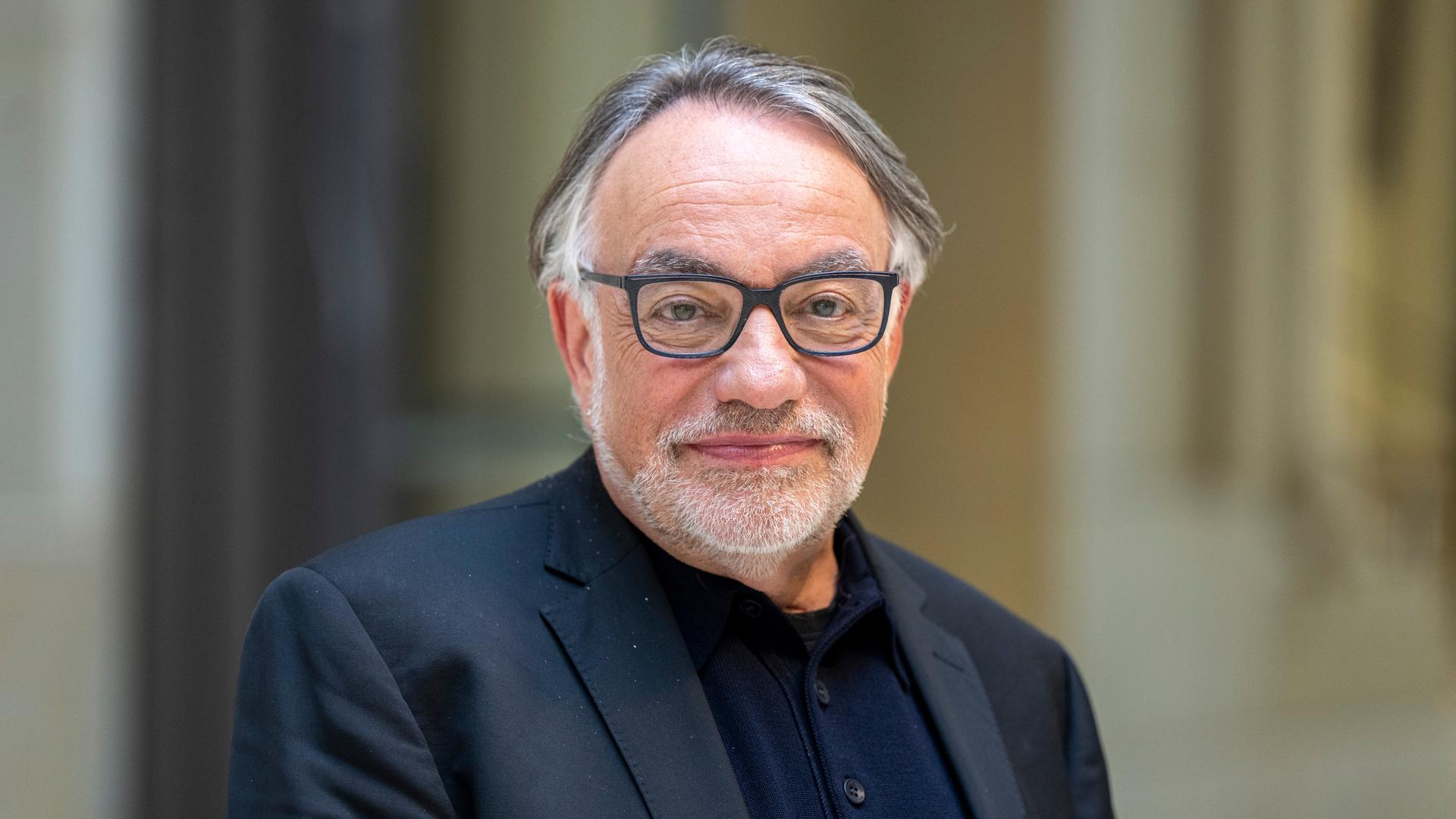 Natan Sznaider im Vorfeld einer Veranstaltung. Er lächelt zurückhaltend, der Hintergrund ist unscharf. Er trägt eine Brille mit dunklem Rand und ein dunkelblaues Sakko. Natan Sznaider im Vorfeld einer Veranstaltung. Er lächelt zurückhaltend, der Hintergrund ist unscharf. Er trägt eine Brille mit dunklem Rand und ein dunkelblaues Sakko.