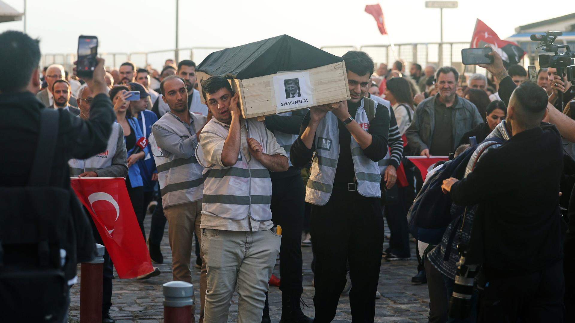 Menschen tragen bei einer Protestkundgebung in Izmir einen symbolischen Sarg mit einem Foto des Oberbürgermeisters Cemil Tugay. Auf dem Sarg steht: „Politisch tot“. Menschen tragen bei einer Protestkundgebung in Izmir einen symbolischen Sarg mit einem Foto des Oberbürgermeisters Cemil Tugay. Auf dem Sarg steht: „Politisch tot“.