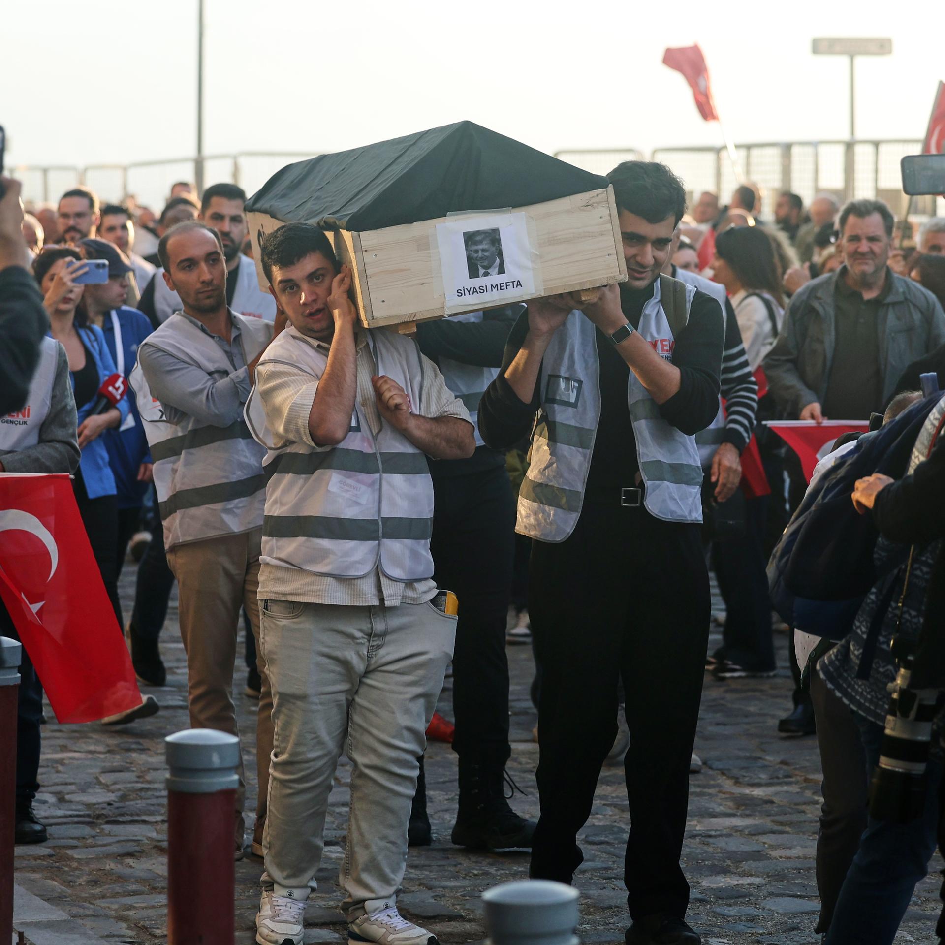Menschen tragen bei einer Protestkundgebung in Izmir einen symbolischen Sarg mit einem Foto des Oberbürgermeisters Cemil Tugay. Auf dem Sarg steht: „Politisch tot“.