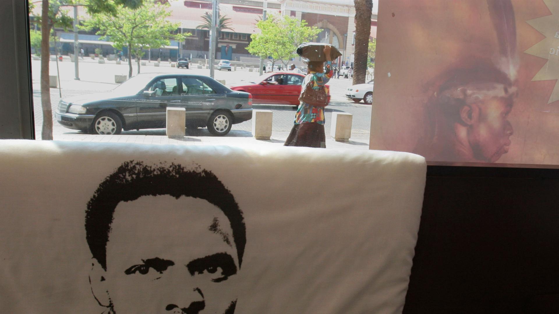 Auf einem Kissen ist das Konterfei des südafrikanischen Bürgerrechtlers Steve Biko gedruckt. Im Hintergrund sieht man durch ein Fenster auf eine Straße. 