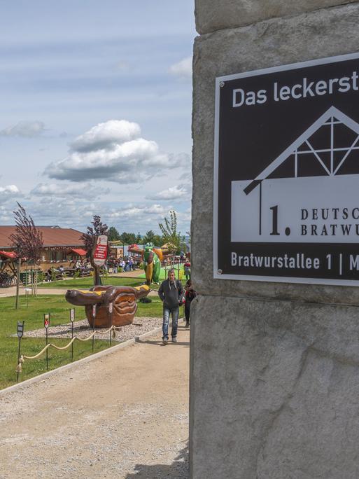 Eingang des ersten Deutschen Bratwurstmuseums in Mühlhausen mit Inschrift und einer mittelalterlichen Ritterfigur mit der Jahreszahl 1404. Museumsgelände im Freien mit einer riesigen Thüringer Bratwurst in Brot mit Senf in Thüringen.