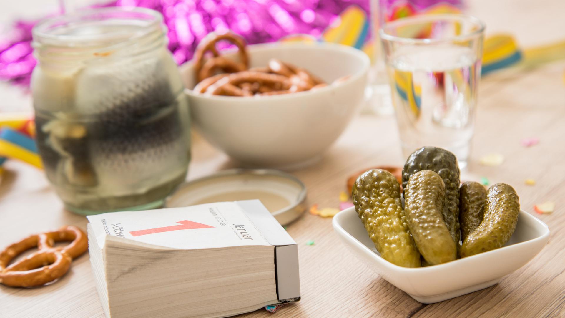 Saure Gurken, Rollmops im Glas und Mini-Salzbrezeln stehen auf einem Tisch zu sehen (gestellte Szene).