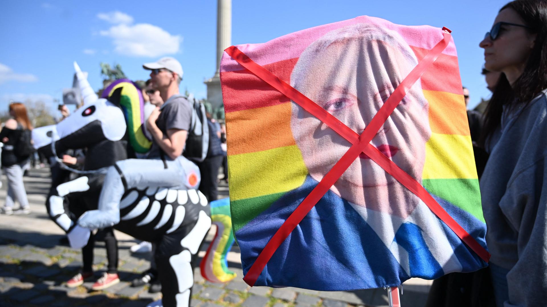 Foto eines Plakats, das ein durchgestrichenes Bild des ungarischen Ministerpräsidenten Viktor Orban auf einer Regenbogenfahne zeigt und während einer Gray Pride Demo am 12. April 2025 hochgehalten