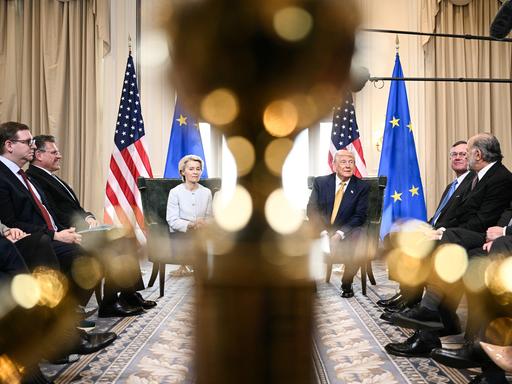 Ursula von der Leyen und Donald Trump sitzen bei einer Pressekonferenz nebeneinander vor US- und EU-Flaggen. Ursula von der Leyen und Donald Trump sitzen bei einer Pressekonferenz nebeneinander vor US- und EU-Flaggen.