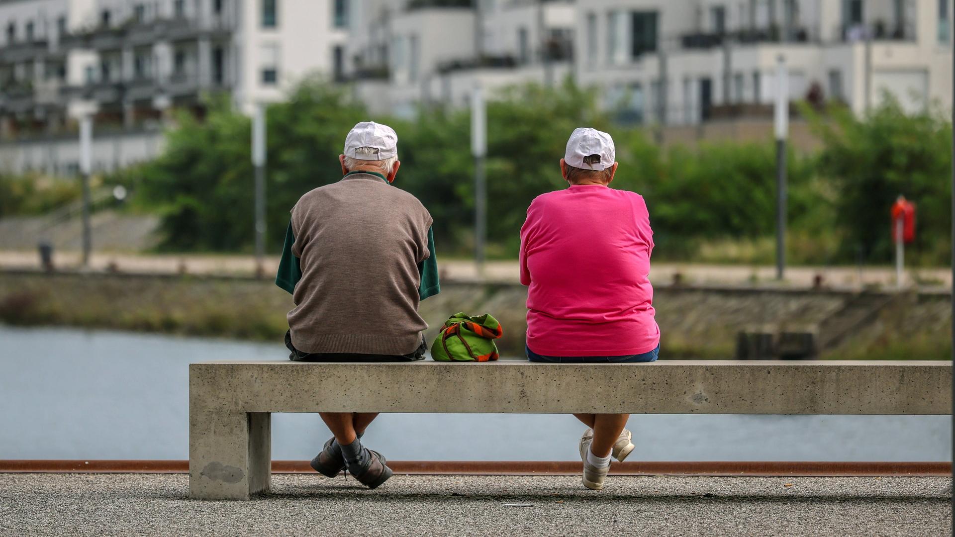 Senioren sitzen auf einer Parkbank am Yachthafen im neuen Stadtquartier von Gelsenkirchen.