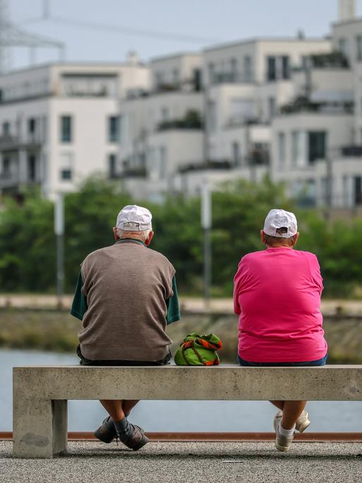 Senioren sitzen auf einer Parkbank am Yachthafen im neuen Stadtquartier von Gelsenkirchen.