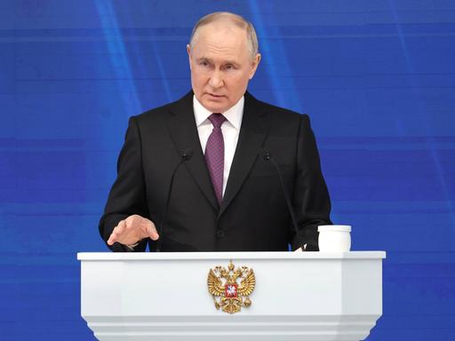 Der russische Präsident Putin steht bei einer Rede an einem weißen Stehpult