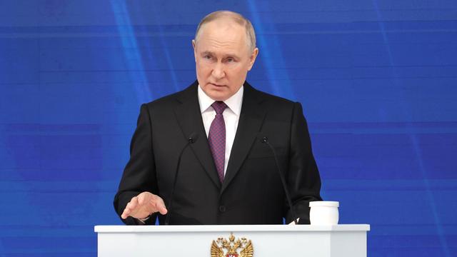 Der russische Präsident Putin steht bei einer Rede an einem weißen Stehpult.