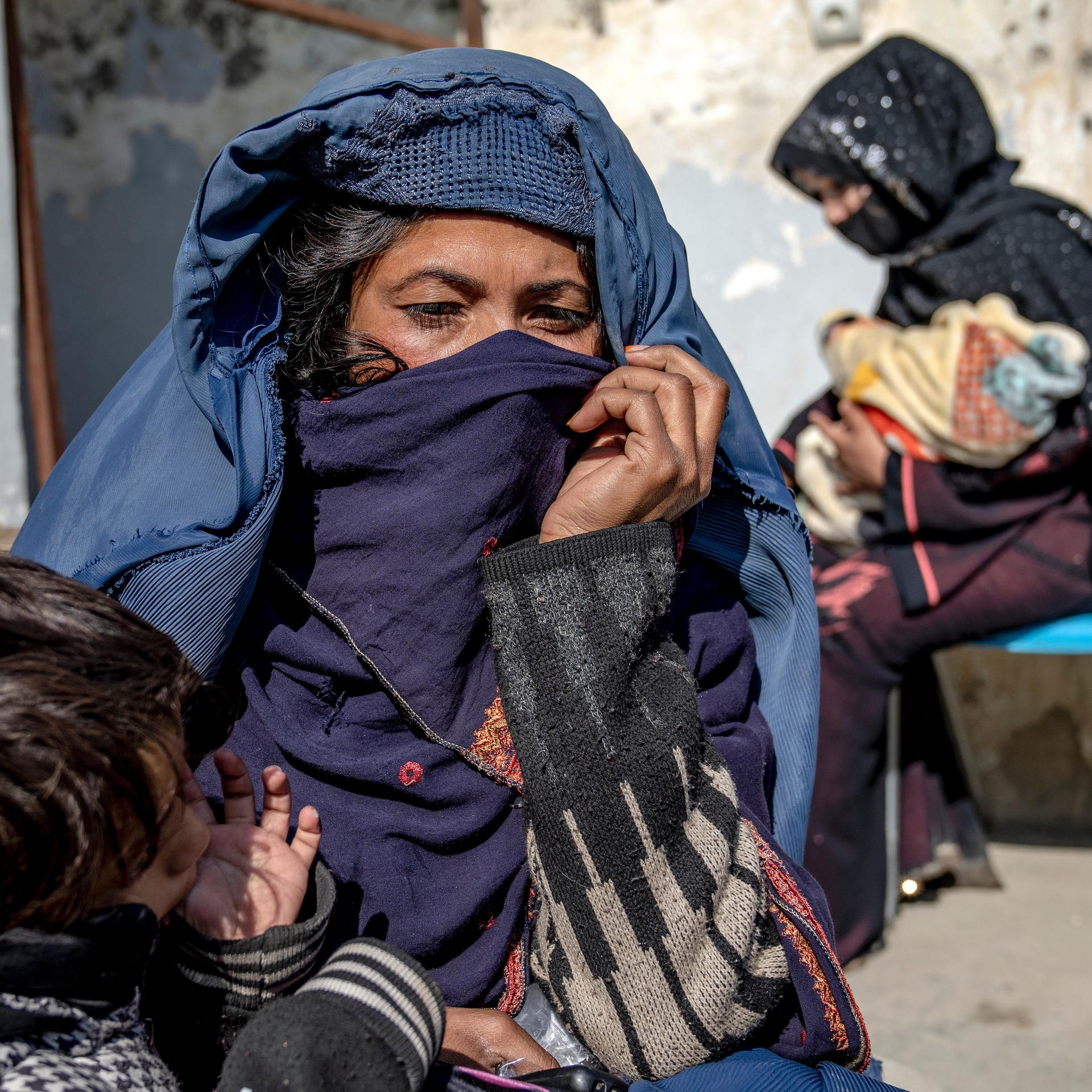Zwei Mütter mit kleinen Kindern im Arm warten vor einer Klinik des UN-Welternährungsprogramms in Kabul in Afghanistan, um Hilfe für ihre unterernährten Kinder zu bekommen.