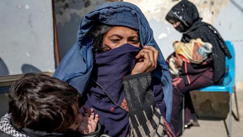Zwei Mütter mit kleinen Kindern im Arm warten vor einer Klinik des UN-Welternährungsprogramms in Kabul in Afghanistan, um Hilfe für ihre unterernährten Kinder zu bekommen.