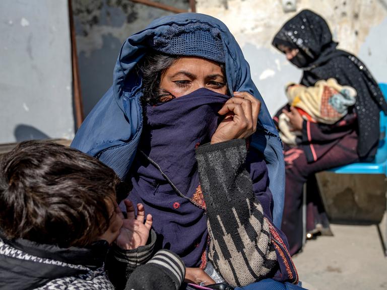 Zwei Mütter mit kleinen Kindern im Arm warten vor einer Klinik des UN-Welternährungsprogramms in Kabul in Afghanistan, um Hilfe für ihre unterernährten Kinder zu bekommen.