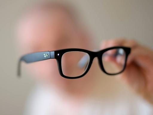 Eine schwarze KI Brille in der Hand eines Menschen
