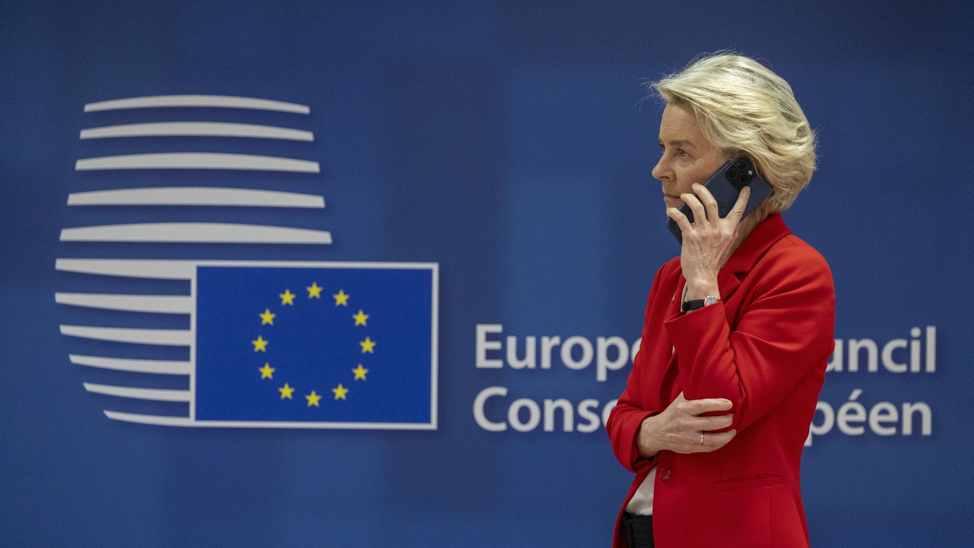 EU-Kommissionspräsidentin Ursula Von der Leyen telefoniert. Im Hintergrund ist das Logo vom Europäischen Rat zu sehen. 