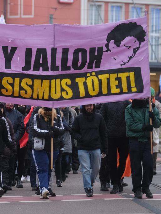 Teilnehmer einer linken Demonstration gehen mit Transparenten und Fahnen durch die Stadt Dessau. Anlass ist der 19. Todestag des Asylbewerbers Oury Jalloh, der am 07. Januar 2005 in einer Polizeizelle ums Leben kam.