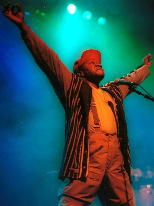 Papa Wemba steht mit ausgebreiteten Armen auf der Bühne