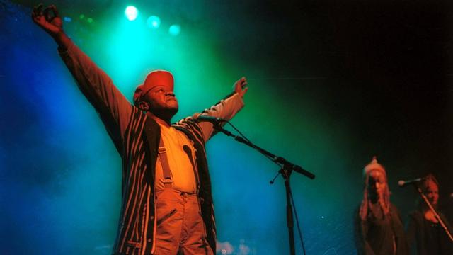 Papa Wemba steht mit ausgebreiteten Armen auf der Bühne