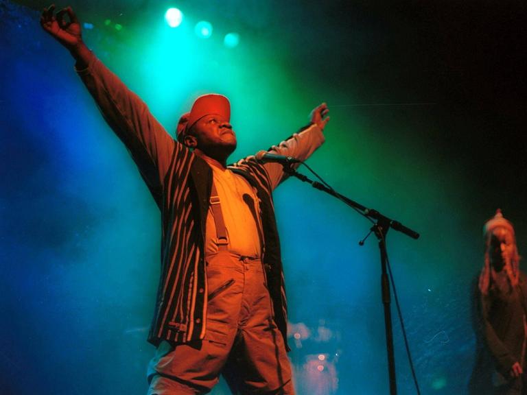 Papa Wemba steht mit ausgebreiteten Armen auf der Bühne