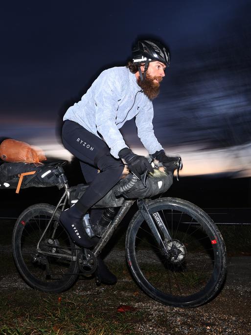 Extrem-Sportler Jonas Deichmann fährt nach seiner Grenzüberfahrt aus der Schweiz mit seinem Fahrrad auf einem Feldweg. Nach seinem Triathlon um die Welt kam Deichmann in Baden-Württemberg an.