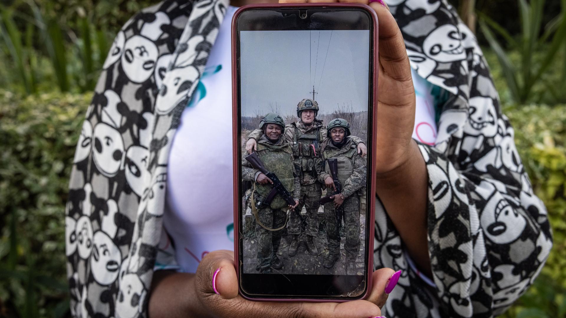 Grace Gathoni Kagombe hält ein Foto ihres Mannes Martin Macharia Mburu (links) in Militäruniform in den Händen. Den Berichten zufolge starb er im Krieg Russlands gegen die Ukraine im Einsatz für Russland.