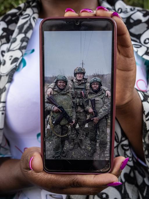 Grace Gathoni Kagombe hält ein Foto ihres Mannes Martin Macharia Mburu (links) in Militäruniform in den Händen. Den Berichten zufolge starb er im Krieg Russlands gegen die Ukraine im Einsatz für Russland.