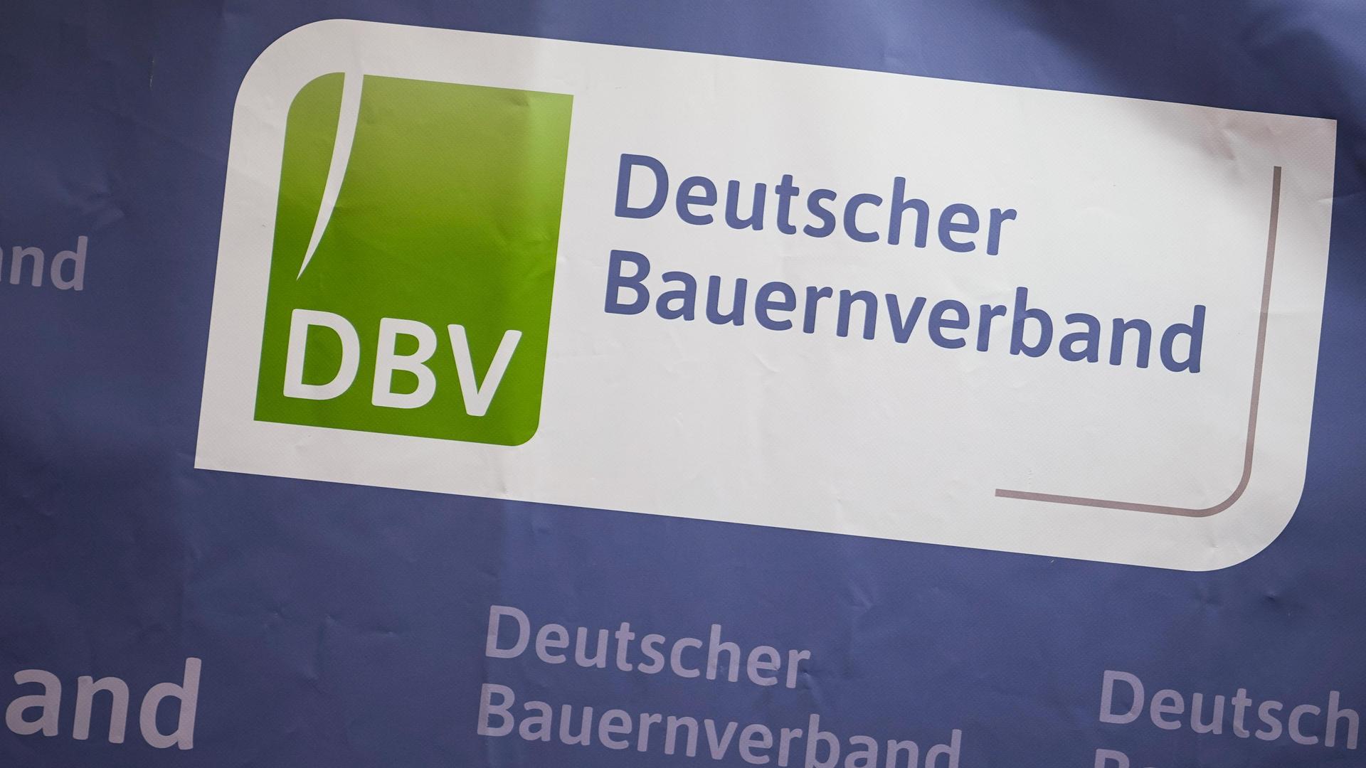 Das Logo des Deutschen Bauernverbandes auf einer blauen Wand. Rundherum mehrmals der Schriftzug des DBV.