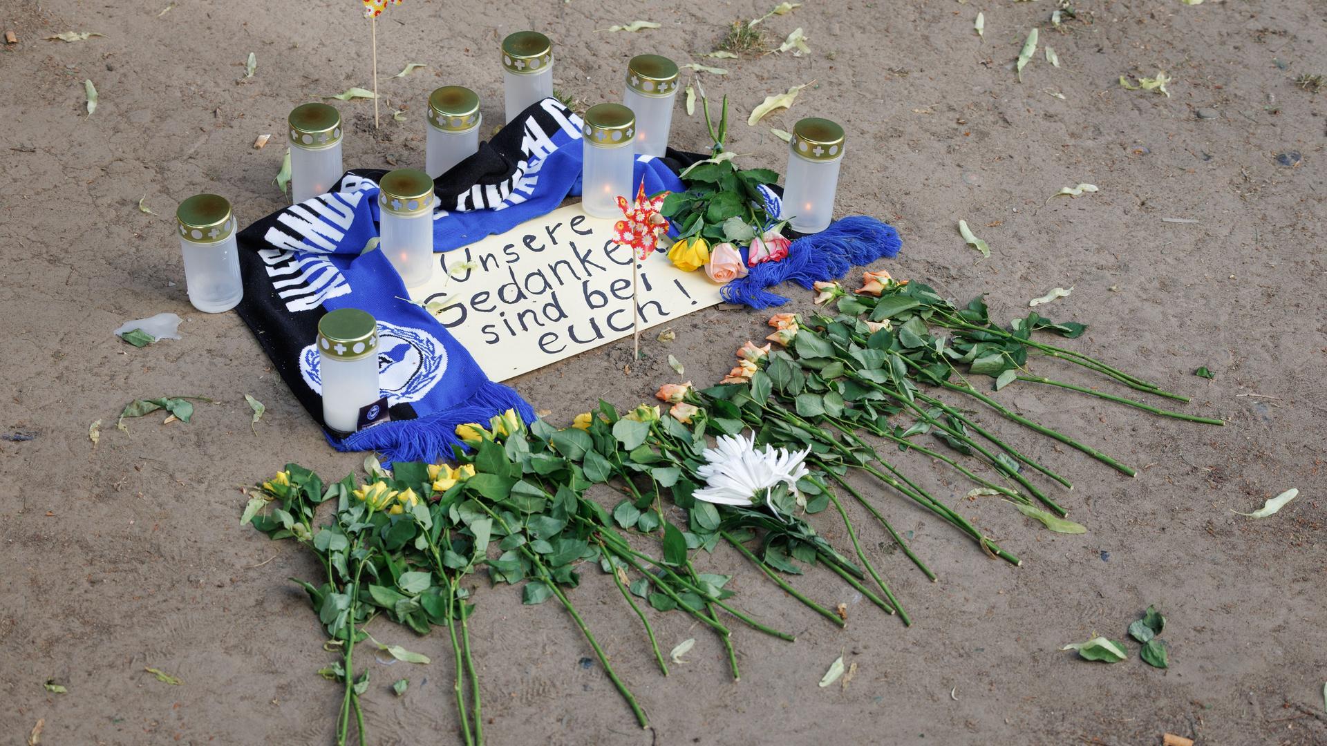 Kerzen und ein Fanschal von Arminia Bielefeld sind an einem Tatort in der Innenstadt zu sehen. 